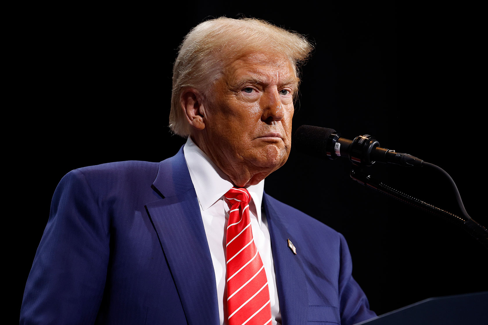 Photo shows Donald Trump standing in front of a mic wearing a red tie